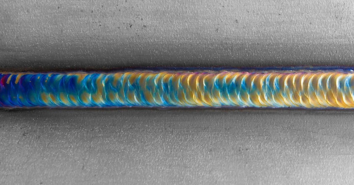 A close-up of a smooth, no-splatter welding seam, ranging in shades of blue and yellow and tinges of red.