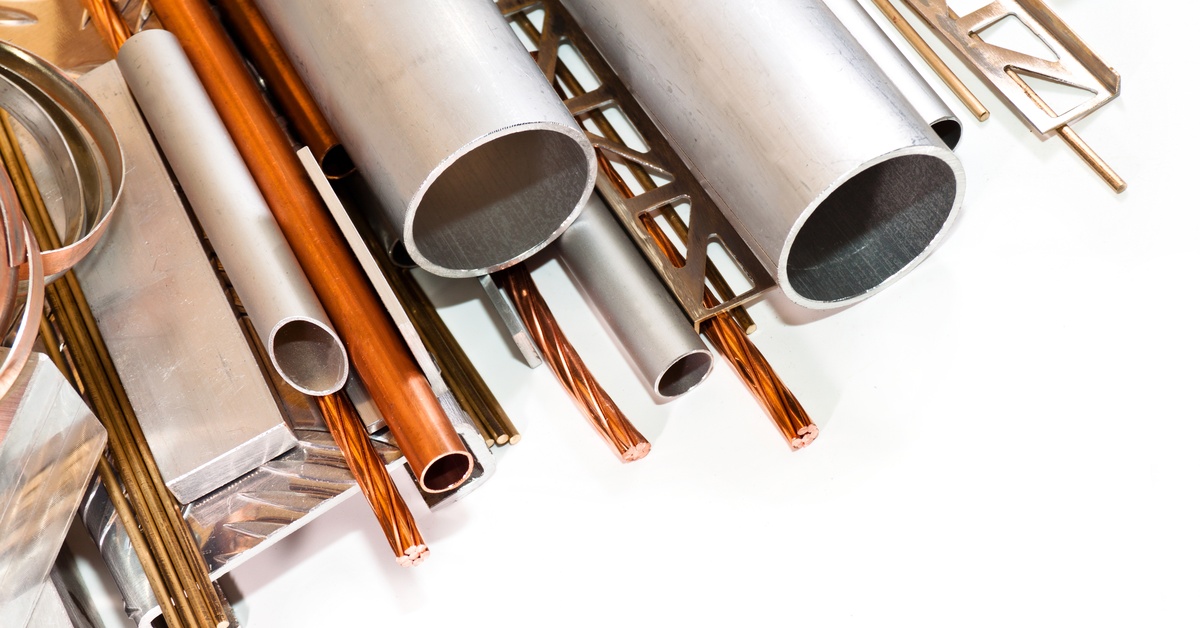 A collection of various metal pieces stacked, including stainless steel rods and blocks, and copper rods.