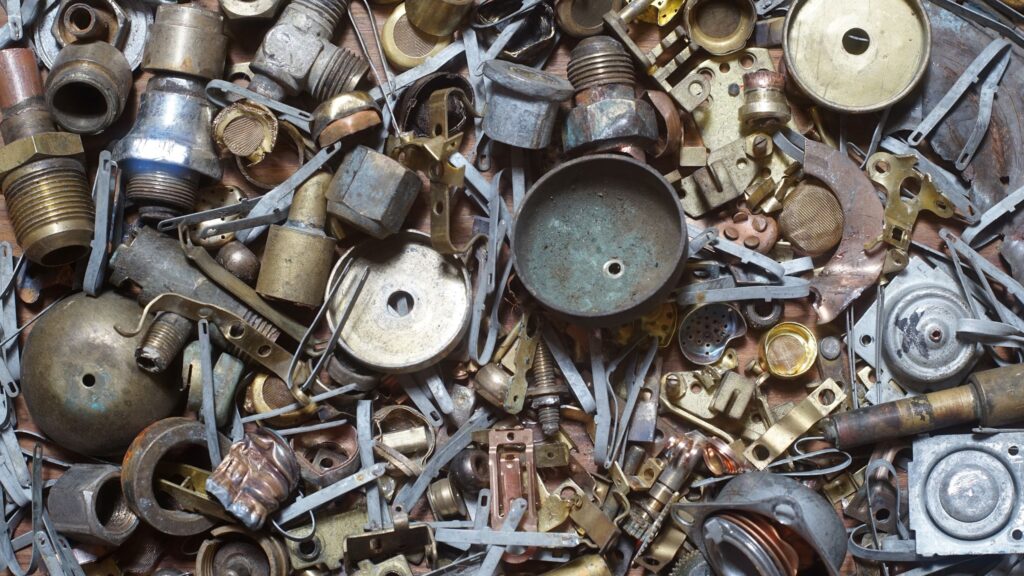 A pile of assorted metal components, such as screws, fasteners, and connections, in materials such as brass.